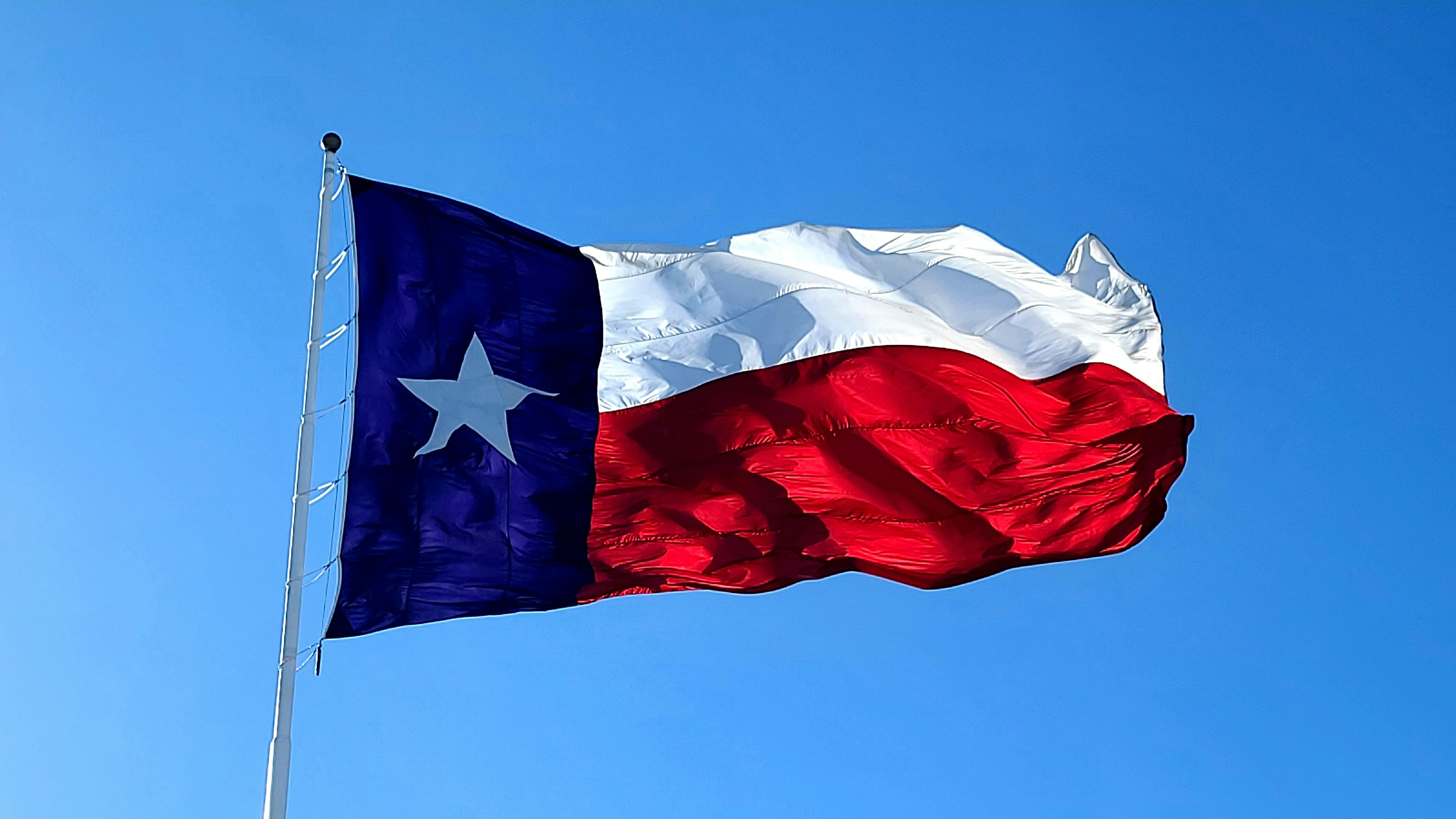 The Texas flag waving against a clear blue sky